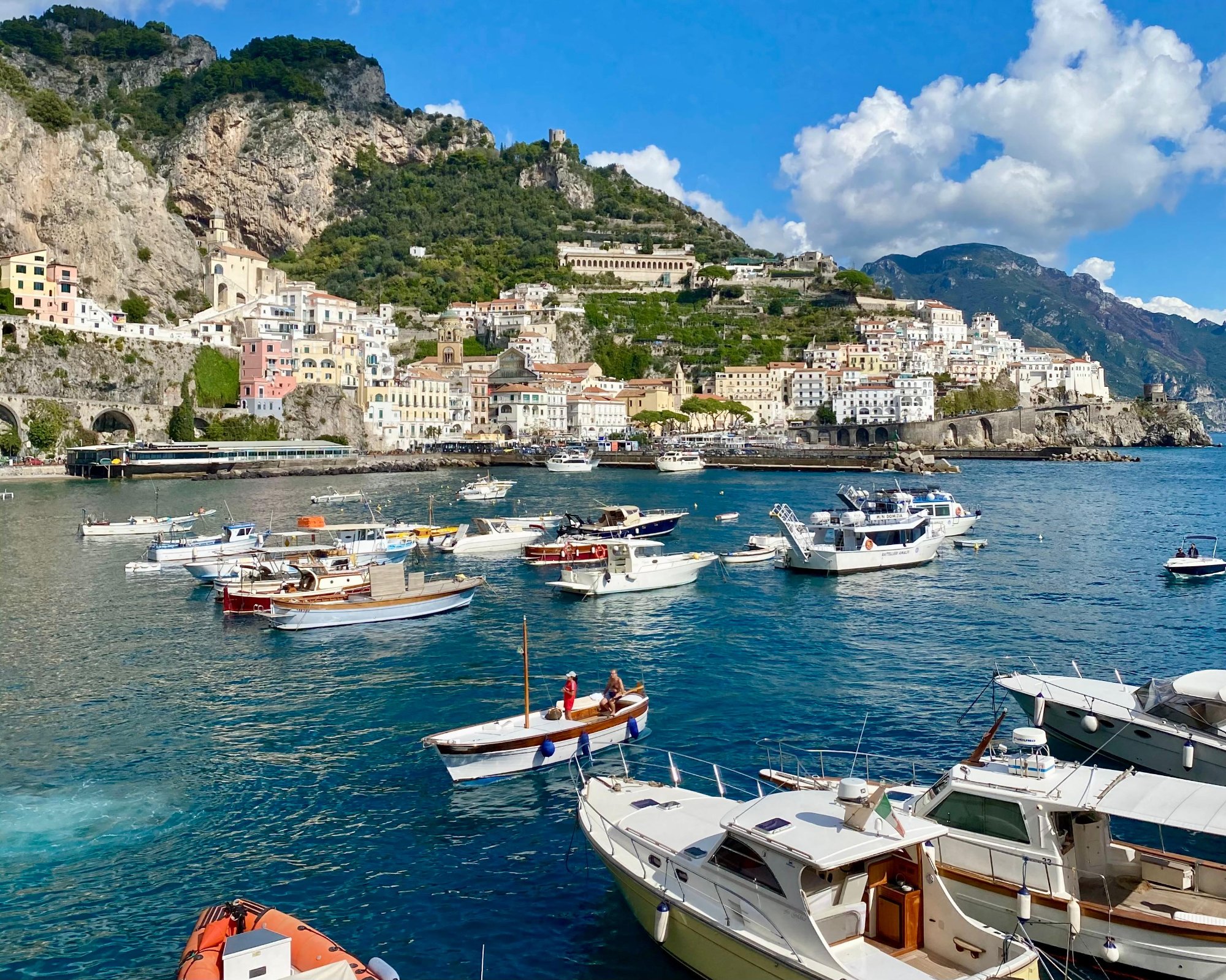 Panoramic view of Amalfi harbor with boats and the historic town nestled between dramatic cliffs, Amalfi Coast, Italy