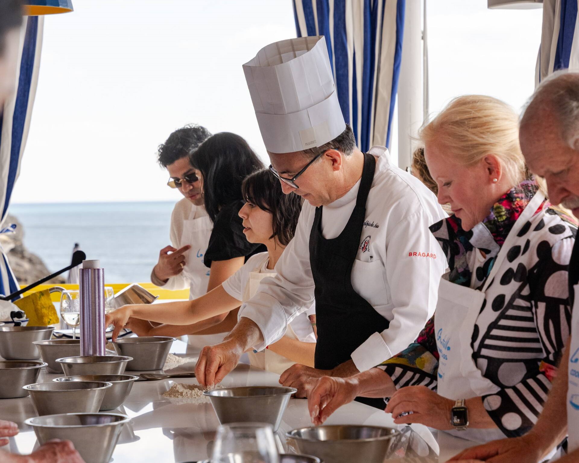 Guests preparing fresh pasta with the chef during a cooking class by the sea at La Gavitella, Amalfi Coast