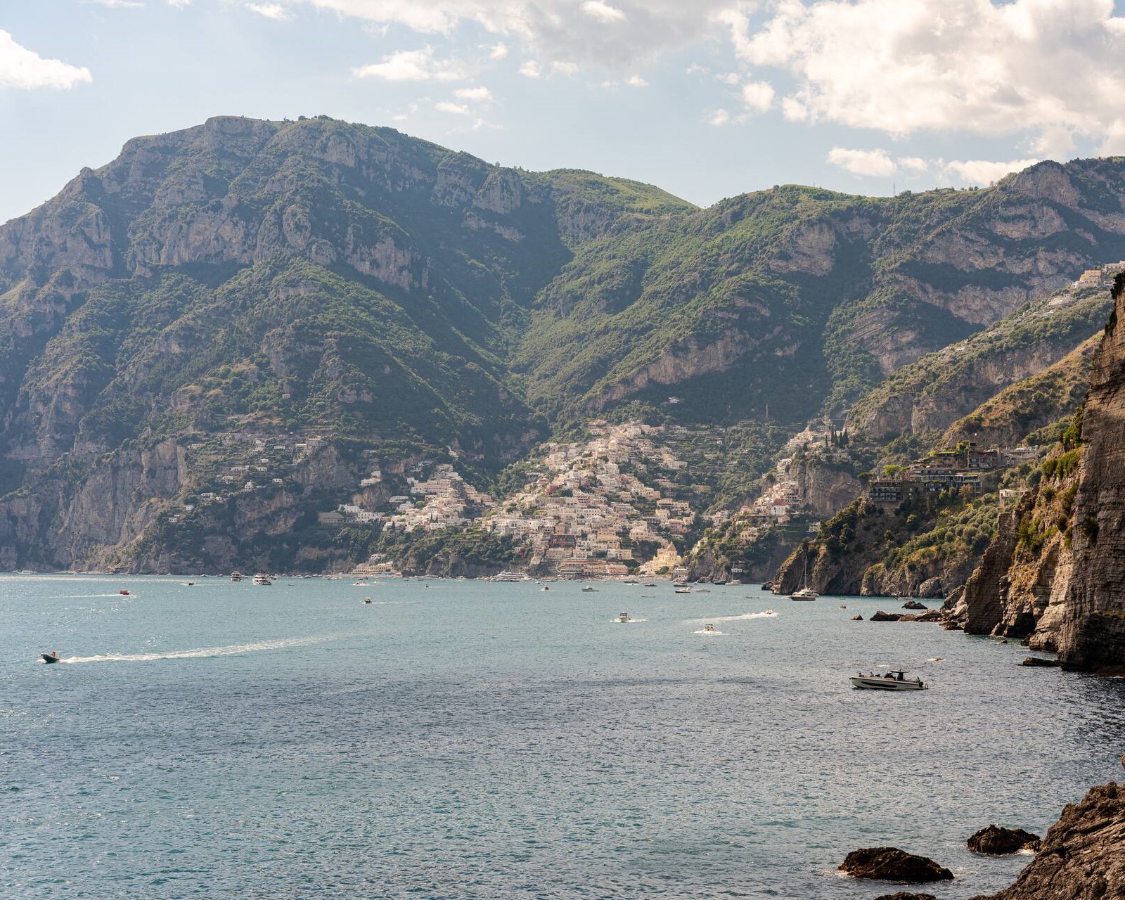 Panoramic view of Positano and the Amalfi Coast from the sea near Praiano, with small boats crossing the bay